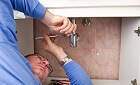 a plumber repairing a broken sink in bathroom